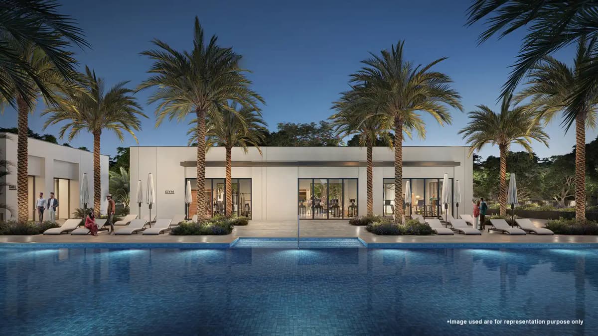 Elegant lap pool at Emaar Velora at the valley, surrounded by lush greenery palm trees and sun bath beds.